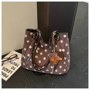 Detaillierte Ansicht der braunen Wildleder Pünktchen Tasche mit Retro Design und Anhänger.