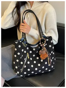 Nahaufnahme Detail der schwarz-weißen Damen Polka Dot Wildleder-Tasche mit Bär-Anhänger.
