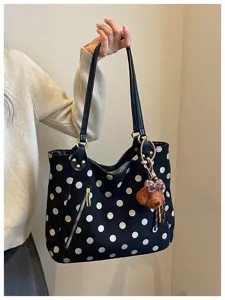 Detailansicht der schwarzen Wildleder-Tote-Bag mit Punkten, Reißverschlusstasche und Bärenanhänger.