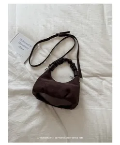 Détail de sac bandoulière en suède marron, sac hobo rétro avec poignée froncée et sangle.