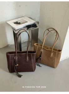 Detail view of retro woven leather tote bag with tassel charm and sleek metal handles.