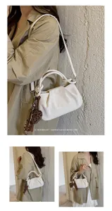 Detailed view of white ruched shoulder bag with leopard heart charm, retro minimalist style.