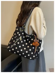 Detailansicht der schwarz-weißen Pünktchen-Wildleder-Tasche mit Bärchen-Anhänger für den Alltag.