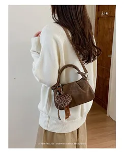 Retro brown pleated cloud bag detail showcasing chic leopard heart charm and stylish handle design.