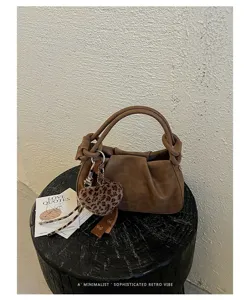Close-up detail of retro brown slouchy hobo bag with unique knot handle and leopard charm.