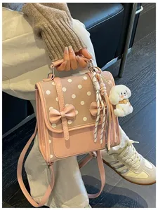 Sweet pink polka dot backpack detail, featuring cute bows, ribbon, and plush dog pendant.