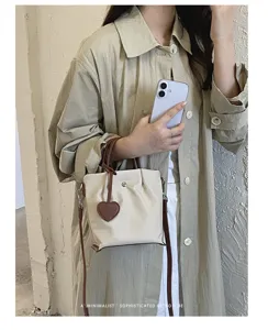Vue détaillée du sac seau en nylon avec poignées en cuir marron et charmant cœur.