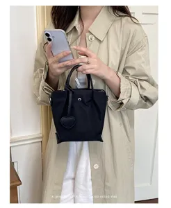Sac cabas noir minimaliste en nylon pour femme, élégant sac seau avec charmant détail cœur.
