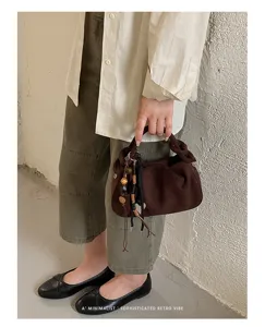Vue détaillée du sac à main plissé marron, texture mate avec pendentif rétro élégant.