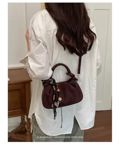 Vue détaillée du sac porté épaule plissé marron mat avec breloque chic et lanière.