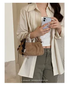 Chic brown suede hobo bag detail, featuring retro pleated design and cute wooden bead charm.