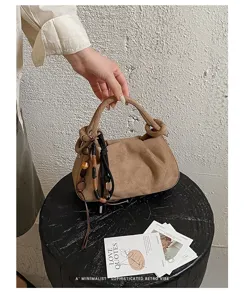 Detail view of the suede ruched handbag, featuring stylish pleated design and chic beaded charms.