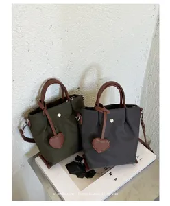 Gros plan du sac seau en nylon avec pendentif cœur et poignée marron dans un décor rétro minimaliste