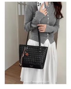 Detail van zwarte geweven lederen shopper, met dubbele schouderbanden en elegante kwastjesbedel.