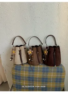 Detailansicht retro Wildleder Eimer Taschen mit süßen Blumenanhängern und schicken Kordeln.
