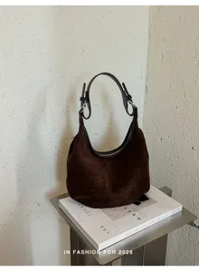 Vue détaillée du sac porté épaule hobo en daim marron foncé sur un magazine éditorial.