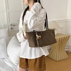 Large capacity brown canvas shoulder tote bag with cute horse charm, casual college commuting style.