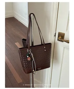 Gedetailleerd overzicht van een bruine geweven lederen tote bag met hanger in retro stijl.