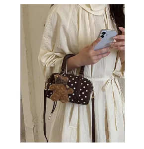 Chic brown polka dot Boston bag with cute plush bear pendant, stylish shoulder cross-body.