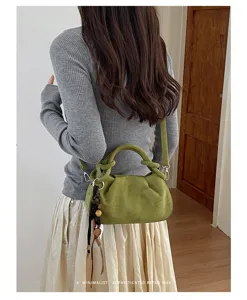 Detailed view of the stylish pleated suede shoulder bag featuring a chic top handle and charm.