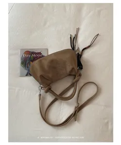 Detailed view of trendy suede pleated shoulder handbag with chic charm and adjustable strap.