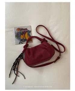 Suede crossbody bag with retro knot handles and chic tassel charm, stylish detail.