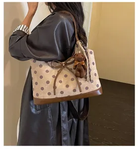 Detailed view of the stylish polka dot shoulder bag with cute bear charm for daily commute.