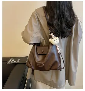 Dettaglio della borsa a tracolla retrò in pelle marrone, elegante shopper con orsetto.