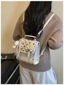 Detailed view of the sweet polka dot backpack with bow charm worn on model's back.