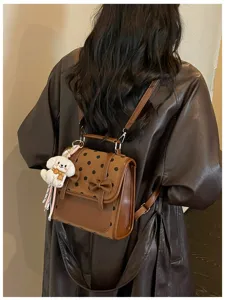 Brown polka dot leather backpack detailed view with cute puppy plush keychain charm.