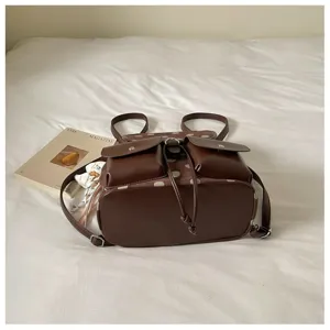 Detailed view of brown polka dot backpack with dual front pockets and secure drawstring closure.