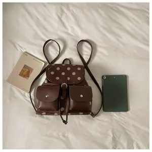 Detailed view of a brown polka dot backpack with front pockets and straps in daily scene.