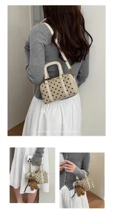 Detailed view of fashionable polka dot boston shoulder bag with cute bear pendant and handles.