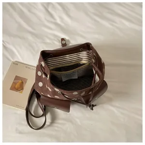 Detail view of the brown polka dot backpack showcasing its drawstring opening and striped interior lining.