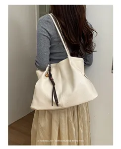 Vue détaillée d'un élégant sac cabas en cuir souple avec pompon tressé et style rétro.