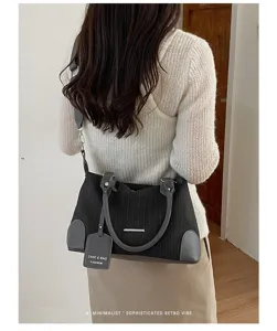 Detailansicht der Retro Boston Tasche mit vertikalen Streifen, elegantem Griff und verstellbarem Gurt.