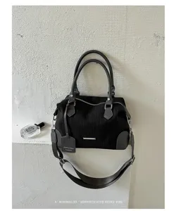Schwarze Boston Handtasche mit vertikalen Streifen, zwei Henkeln und langem Schultergurt.