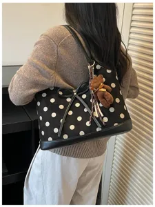 Black and white polka dot shoulder bag detail view with bow and cute bear pendant.