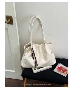 Vue détaillée d'un élégant sac cabas souple beige rétro minimaliste avec breloque tressée.