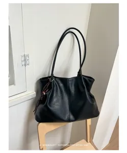 Détail de sac cabas souple en cuir noir, design rétro minimaliste avec doubles bretelles.