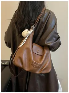 Borsa a tracolla vintage in pelle marrone con ciondolo orsetto e grande capienza.