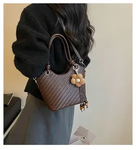 Détail de sac seau tressé chic avec pendentif fleur élégant et pampilles, design tendance.