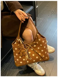 Detailed view of brown polka dot shoulder bag featuring cute bear pendant and bow design.