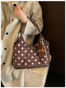 Detail view of the brown polka dot suede hobo shoulder bag with cute bow and bear pendant.