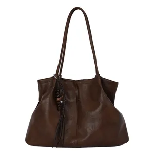 Sac cabas souple en cuir marron pour femme, grand sac porté épaule avec pompon élégant.