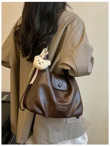 Vista di dettaglio dello zaino e borsa a spalla in pelle marrone vintage con ciondolo.