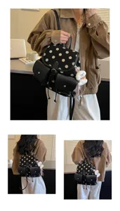 Detail shot of black and white polka dot backpack with dual front pockets and cute charm.