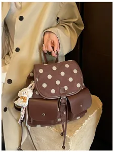 Brown polka dot backpack detail showing stylish front pockets and cute puppy pendant accessory.