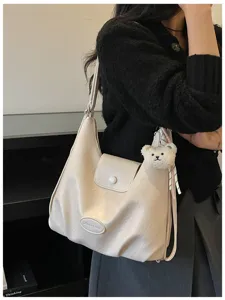 Borsa a spalla beige da donna elegante con ciondolo a forma di orsetto per uso quotidiano.