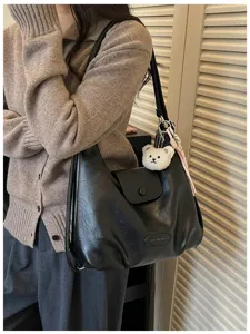 Vista ravvicinata dettagliata di una borsa a spalla retrò in pelle nera con orsetto.